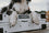 A dog laying on top of a collapsed white collapsible dog crate with their paws hanging over the edge