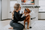 a girl petting her golden retriever sitting in a white collapsible dog crate in a well lit living room